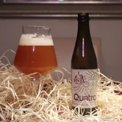 Szklanka i butelka piwa Quatro. Różnica między IPA a APA w doborze słodów i odmian chmielu jest kluczowa dla smaku.