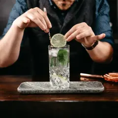 Barman kończy przygotowanie drinka z lodem, miętą i limonką. Czy wódka jest gazowana? To pytanie pozostaje bez odpowiedzi.