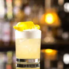 Idealny domowy "Whisky Sour" z idealną pianką z białka, ozdobiony skórką cytryny.