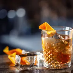 Idealne Old Fashioned w domu: wybór bazy i bittersów. Bursztynowy trunek z lodem i skórką pomarańczy.