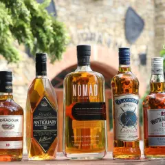 Jak odczytać etykietę szkockiej whisky: Islay, Highlands, Speyside. Pięć butelek whisky na drewnianym stole.