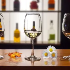 Trzy kieliszki na drewnianym blacie. Jak usunąć zapach alkoholu z kieliszka przed ponowną degustacją? Jesienne liście i kwiaty dodają uroku.