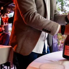 Mężczyzna otwiera butelkę szampana Cattier. Różnica między prosecco, cavą i szampanem tkwi w metodzie produkcji.