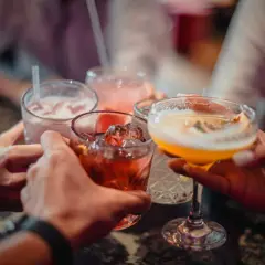 Ludzie wznoszą toasty kolorowymi drinkami. Zastanawiasz się, ile kcal ma litr wódki?