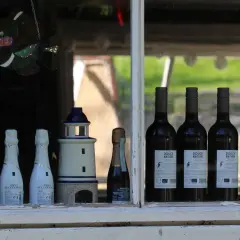 Witrażowa rybka wisi nad butelkami wina i latarniami morskimi. Jak sprawdzić rocznik wina, kiedy starsze nie zawsze oznacza lepsze?
