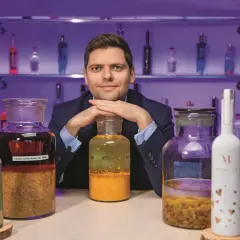 Ekspert prezentuje najlepsze techniki produkcji wódek rzemieślniczych (craft vodka), otoczony butelkami i słoikami z nalewami.