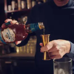 Mężczyzna nalewa whisky Chivas Regal do miarki. Czy whisky podnosi cukier? To pytanie zadaje sobie wielu, ale alkohol sam w sobie nie zawiera cukru.