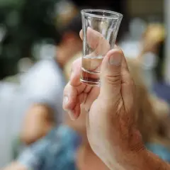 Dłoń trzyma kieliszek z alkoholem. Czy po whisky jest kac? Zależy od ilości i jakości trunku.