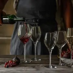 Skutki napowietrzania wina (dekantacja) widoczne podczas przelewania do karafki. Wino w kieliszku, obok winogrona i figi.