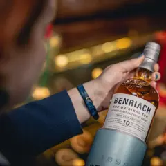 Dobre whisky na prezent: butelka Benriach The Original Ten w rękach kobiety, idealna na upominek.