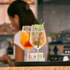 Dwa drinki: pomarańczowy Aperol Spritz i jasny Hugo. Różnica między aperol spritz a hugo w składnikach i kaloryczności jest widoczna.