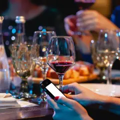 Zanim sięgniesz po alkohol, pomyśl o "podkładzie". Na stole wino, przekąski i telefon. Unikaj skutków picia alkoholu na pusty żołądek.