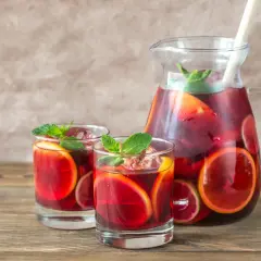 Domowa sangria z owocami i winem czerwonym: orzeźwiający napój w dzbanku i szklankach, ozdobiony plasterkami cytrusów i miętą.
