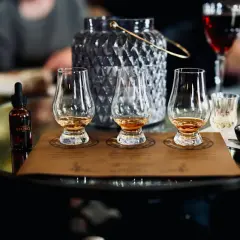 Degustacja whisky metodą tulipana: jak poczuć torf, wanilię i dym. Na stole kieliszki, buteleczka z whisky i czekoladka.