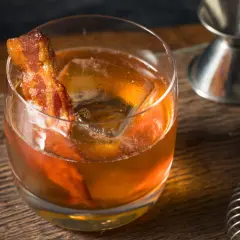 Whisky z boczkiem, czyli jak zrobić infuzowaną whisky z boczkiem (fat washing) techniką barmańską. Drink z lodem i plasterkiem boczku.