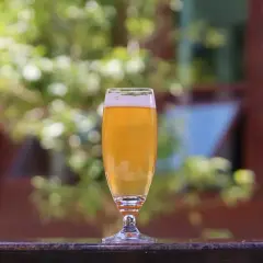 Szklanka piwa, wolna od wad takich jak diacetyl, aldehyd octowy i fenole, na tle zieleni.