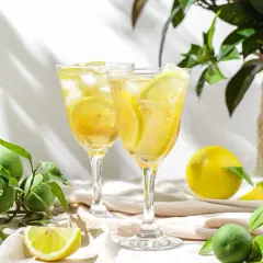 Orzeźwiający drink z limoncello, lodem i plasterkami cytryny, otoczony świeżymi owocami cytrusowymi.