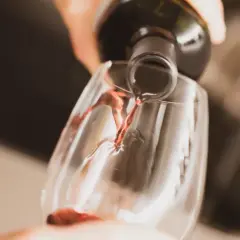 Czerwone wino leje się z butelki do kieliszka. Czy wino się psuje? Nie, jeśli jest świeże i dobrze przechowywane.