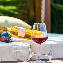 Butelka wina i kieliszek czerwonego wina na leżaku. Czy alkohol wyparowuje, gdy używamy taniego wina do gotowania?