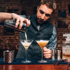 Barman przelewa drinka do kieliszka, tworząc idealną piankę z białka. Poznaj przyczyny mętnienia drinków typu sour.