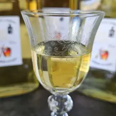 Szklanka z domową whisky "pudrową" z miodem i przyprawami, w tle butelki. Idealna na zimowe wieczory.