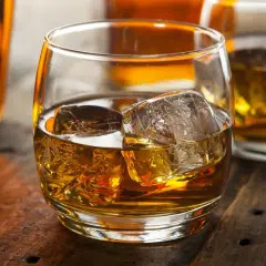 Szklanka whisky z lodem na drewnianym stole. Dowiedz się o różnicy między whisky szkocką a kanadyjską i irlandzką wymogi prawne.
