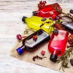 Kolorowe nalewki w butelkach, ozdobione owocami i ziołami. Dowiedz się, jak usunąć intensywny zapach alkoholu z domowych nalewek.