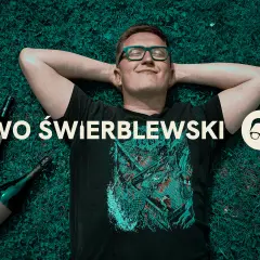 Przyczyny "łez" na ściankach kieliszka mówią o zawartości alkoholu. Mężczyzna leży na trawie obok butelek.