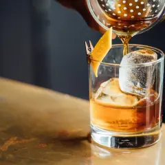 Whisky z colą: profanacja czy dopuszczalny mix? Bursztynowy trunek z lodem i skórką pomarańczy, nalewany ze shakera.