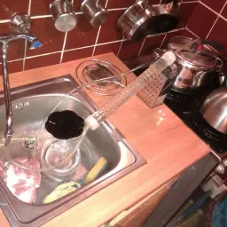 Domowy sposób na whisky z bimbru: destylator w zlewie, garnki na kuchence i szklana rurka.