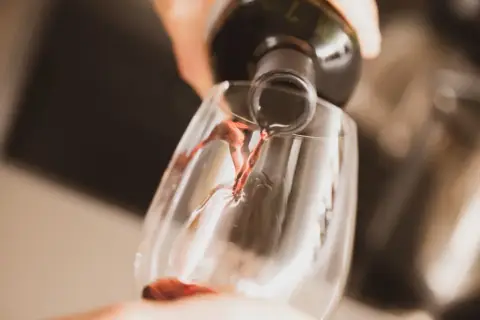 Czerwone wino leje się z butelki do kieliszka. Czy wino się psuje? Nie, jeśli jest świeże i dobrze przechowywane.