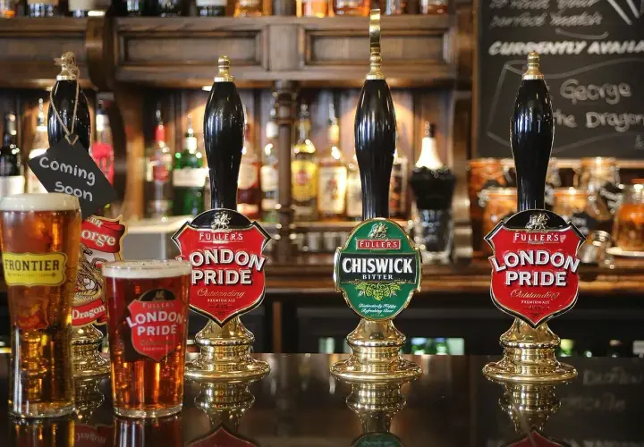 Jak zaplanować zapas piwa na imprezę? Keg vs butelki kalkulacja. Piwo London Pride i Chiswick Bitter na ladzie pubu.