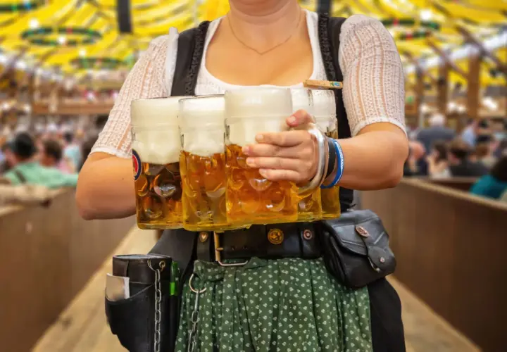 Kelnerka w tradycyjnym stroju niesie kufle piwa. Obrazek nawiązuje do tego, jakie są tradycje piwne w Czechach a jakie w Niemczech kultura picia.