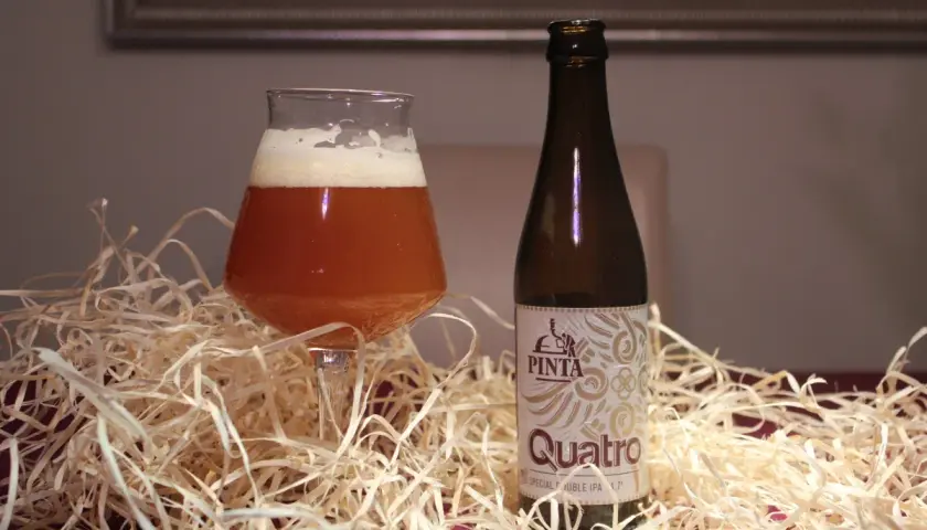 Szklanka i butelka piwa Quatro. Różnica między IPA a APA w doborze słodów i odmian chmielu jest kluczowa dla smaku.