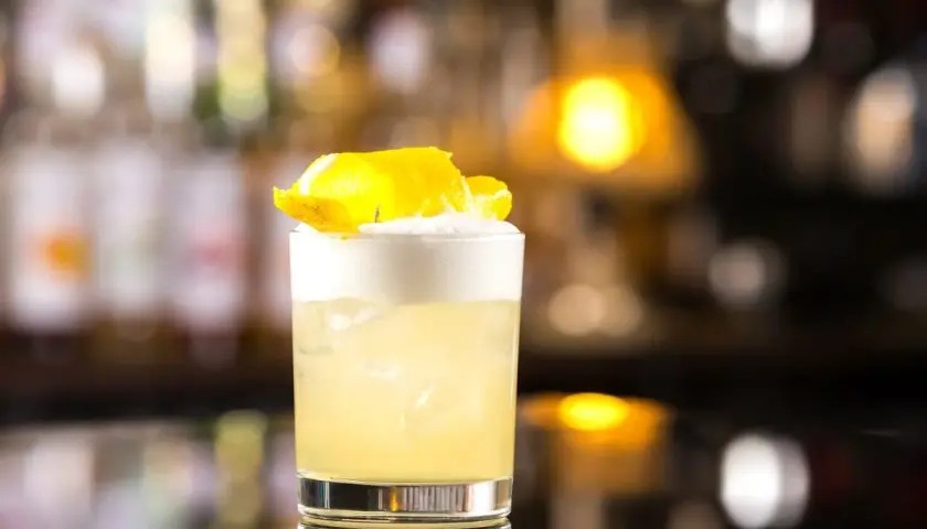 Idealny domowy "Whisky Sour" z idealną pianką z białka, ozdobiony skórką cytryny.