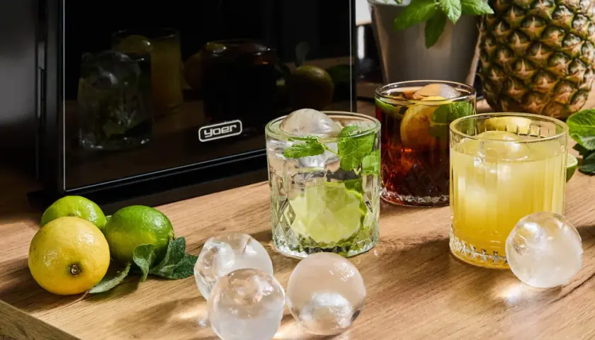 Jak dobrać lód do drinka: kostki, kule czy lód suchy? Na stole cytryny, limonki, drinki i różne rodzaje lodu.