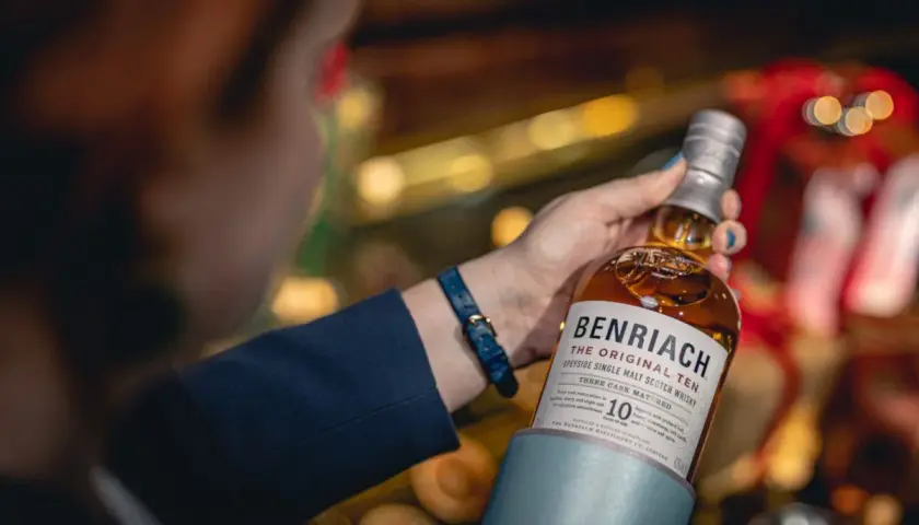 Dobre whisky na prezent: butelka Benriach The Original Ten w rękach kobiety, idealna na upominek.
