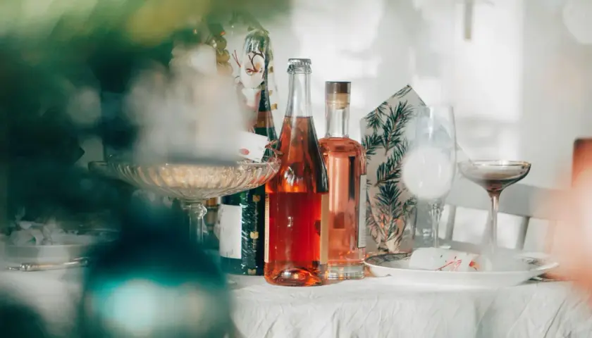 Butelki z różowym winem i kieliszki na stole. Jak zaplanować menu drinków na wesele, ile alkoholu kupić?