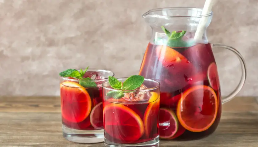 Domowa sangria z owocami i winem czerwonym: orzeźwiający napój w dzbanku i szklankach, ozdobiony plasterkami cytrusów i miętą.