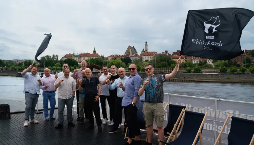 Grupa mężczyzn świętuje na statku, unosząc kieliszki. Czy warto inwestować w whisky kolekcjonerską? Portfel inwestycyjny 2026.