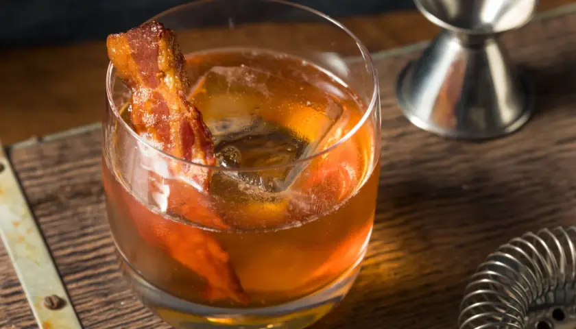 Whisky z boczkiem, czyli jak zrobić infuzowaną whisky z boczkiem (fat washing) techniką barmańską. Drink z lodem i plasterkiem boczku.