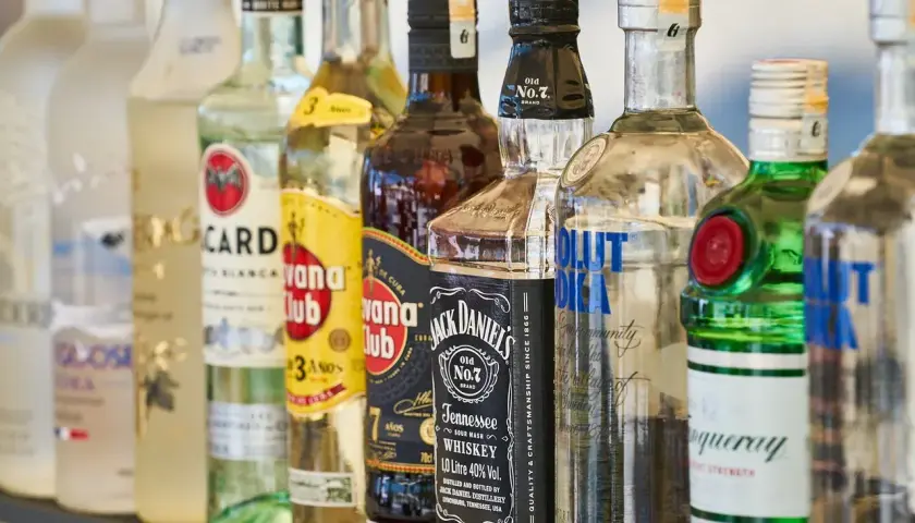 Rząd butelek alkoholi, w tym wódki, whisky i ginu, na barze.