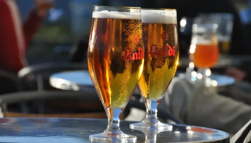 Dwa kieliszki złocistego piwa z pianką, idealne do degustacji aromatów i goryczki dzięki najlepszym technikom chmielenia na zimno (dry hopping).