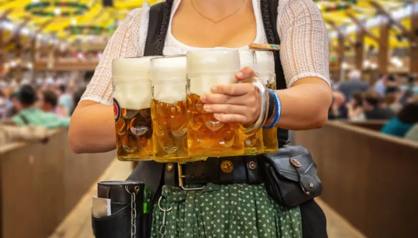 Kelnerka w tradycyjnym stroju niesie kufle piwa. Obrazek nawiązuje do tego, jakie są tradycje piwne w Czechach a jakie w Niemczech kultura picia.
