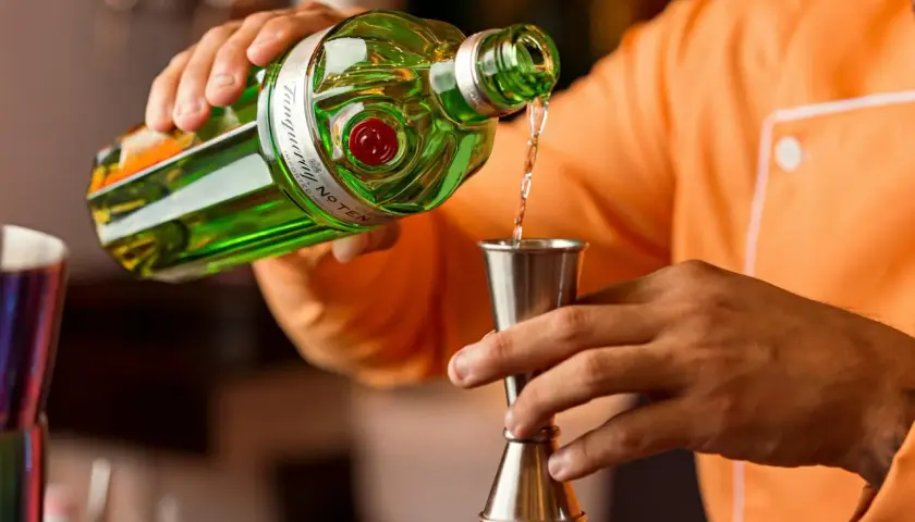 Barman nalewa gin do jiggera. Standardowy shot to 45 ml, a jigger barmański ma proporcje 25/50 ml.