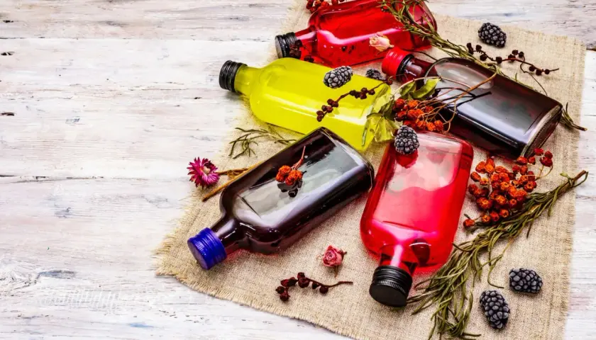 Kolorowe nalewki w butelkach, ozdobione owocami i ziołami. Dowiedz się, jak usunąć intensywny zapach alkoholu z domowych nalewek.