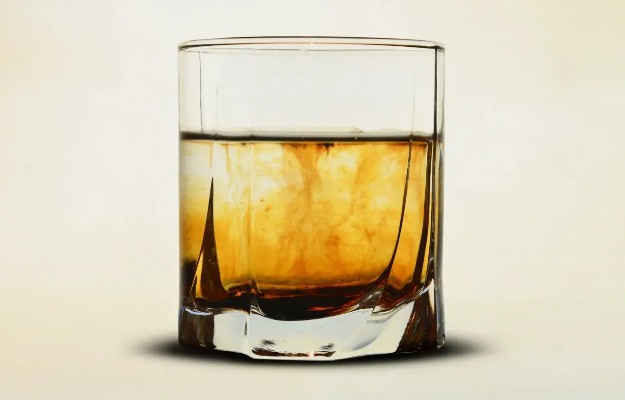 Krople barwnika tworzą wiry w szklance, imitując proces jak zrobić domową whisky.