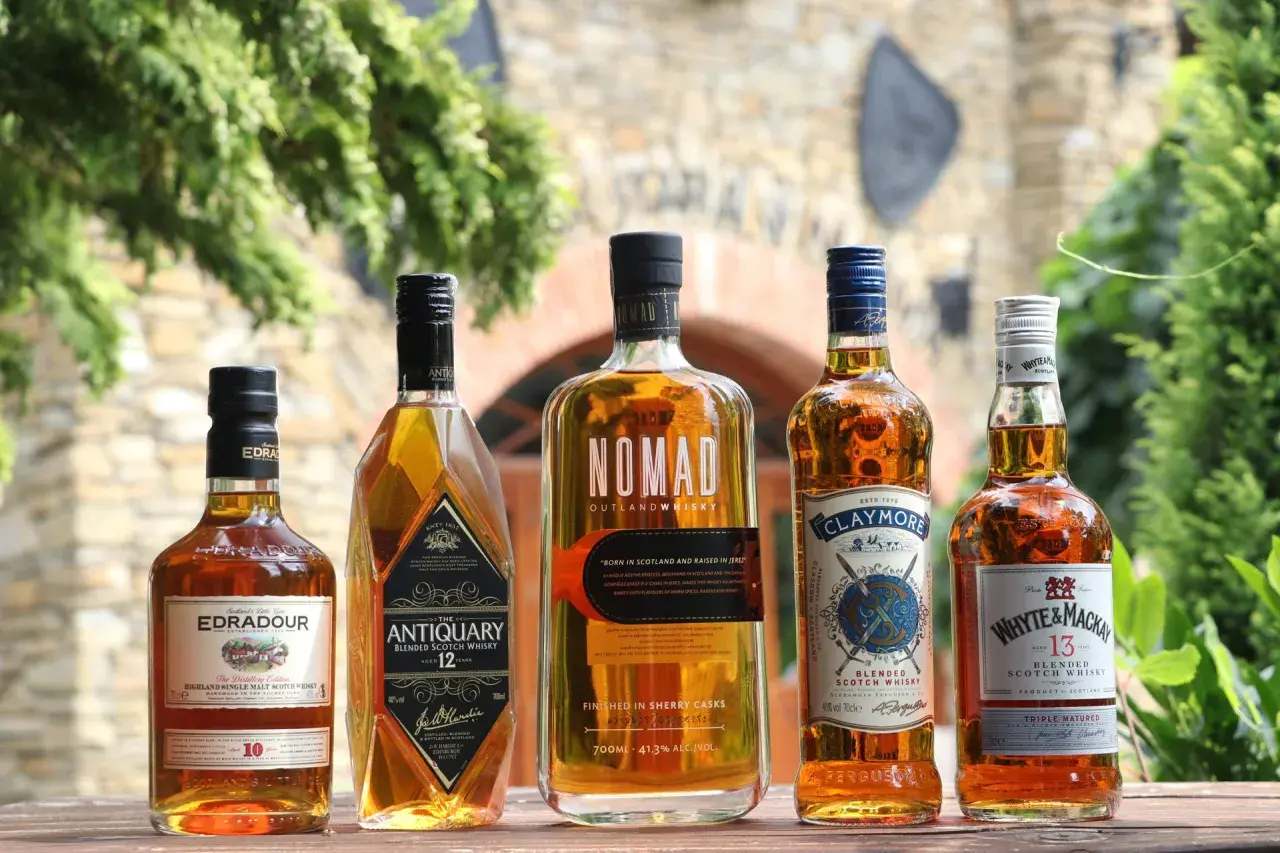 Jak odczytać etykietę szkockiej whisky: Islay, Highlands, Speyside. Pięć butelek whisky na drewnianym stole.