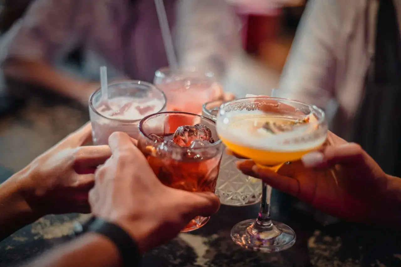 Ludzie wznoszą toasty kolorowymi drinkami. Zastanawiasz się, ile kcal ma litr wódki?