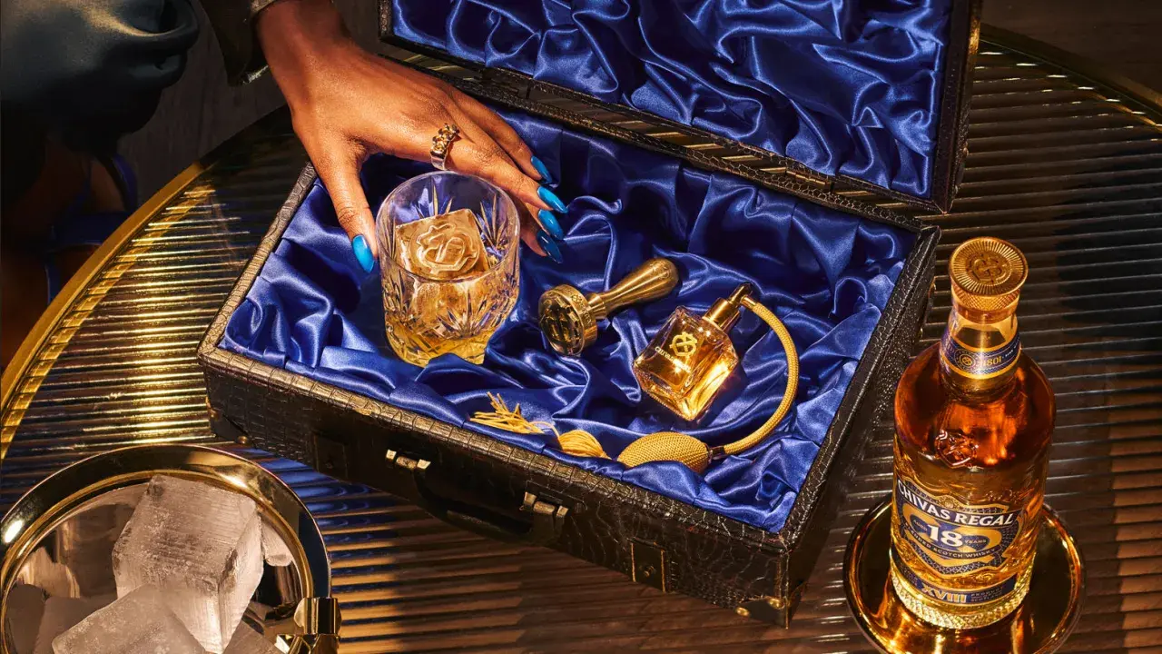 Skutki zbyt niskiej temperatury serwowania: dlaczego nie mrozić whisky. Elegancki zestaw z butelką Chivas Regal 18, szklanką z lodem i złotymi akcesoriami.